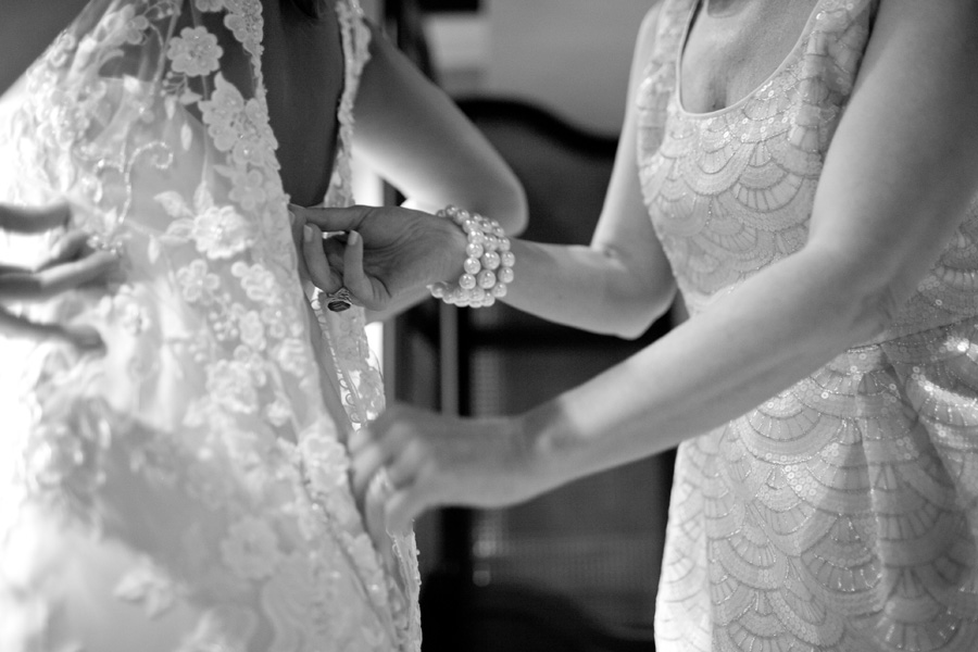 mom helping daughter into wedding dress